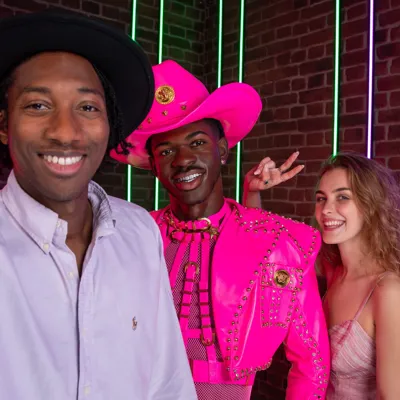 Two people talking a selfie with the figure of Lil Nas X
